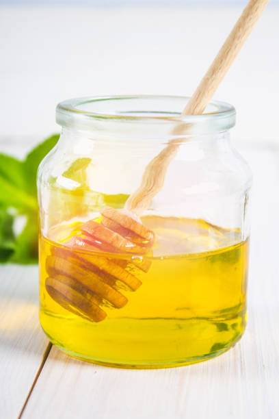 istock A honey jar with a spoon on a white table. In the background, mint. 803510396