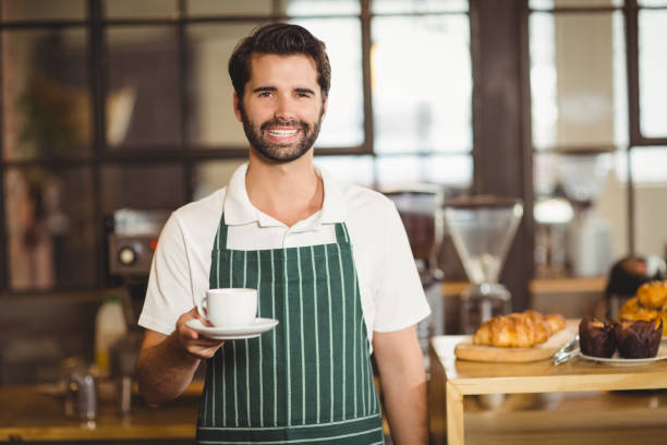 istock Smiling barista holding a cup of coffee 803524756