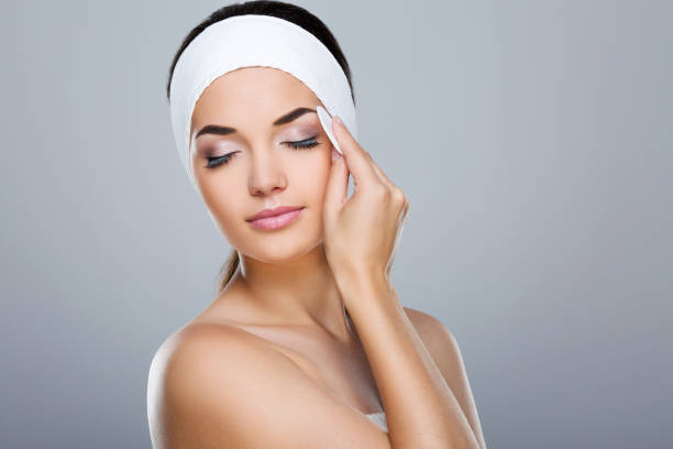 istock Woman with white headband touching face with cotton pad 803577530
