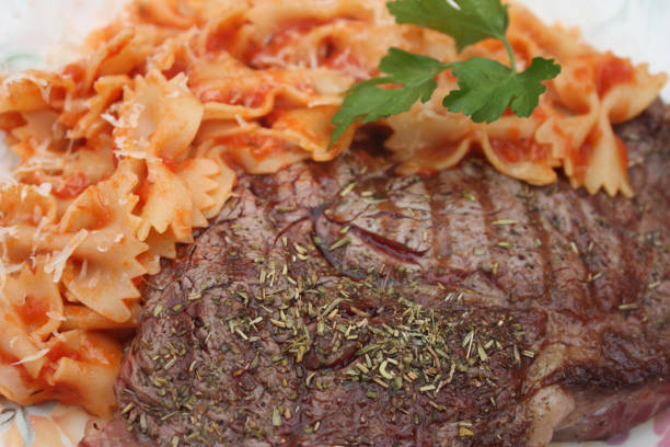 Grilled Beef steak  Butterfly pasta "Farfalle" in tomato sauce Grilled Beef steak  Butterfly pasta "Farfalle" in tomato sauce grillade stock pictures, royalty-free photos & images
