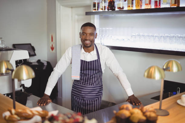 istock Portrait of smiling waiter standing counter 803594016