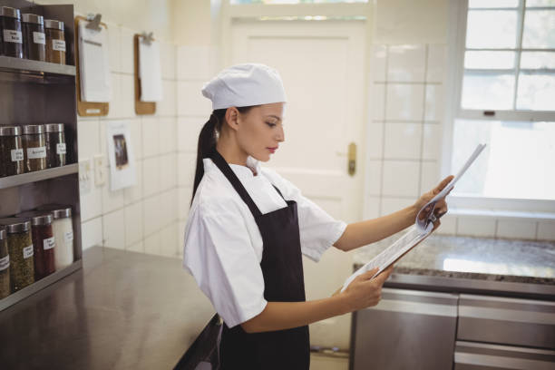 istock Female chef looking at clipboard in the commercial kitchen 803596744