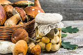 Boletus mushrooms marinated in jar on rustic wooden table, autumnal preserves preparing