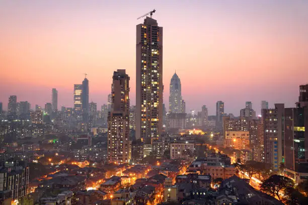 Panoramic view of south central Mumbai - the financial capital of India - at golden hour showing vast contrast in the living conditions of people with dwellings of lower middle class in foreground and towers where elite stay in the far background.