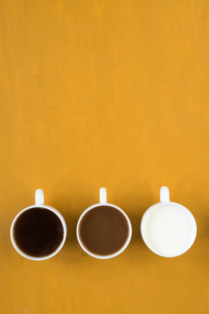 istock Three cups with coffee and milk on yellow background 803612164