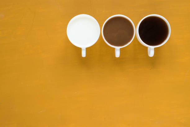 istock Three cups with coffee and milk on yellow background 803612248