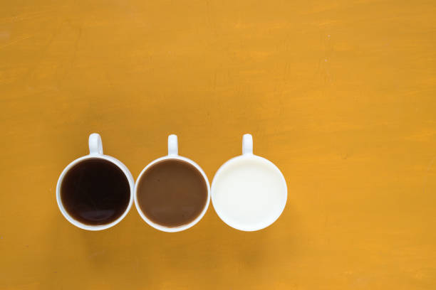 istock Three cups with coffee and milk on yellow background 803612304