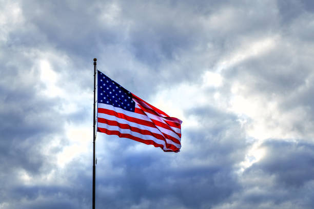 istock American flag flapping in dark ominous sky 803616576