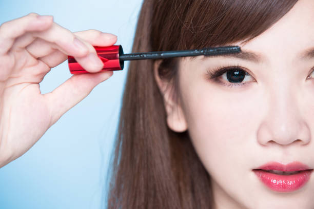 woman take mascara beauty woman take mascara on the blue background asian eyebrows stock pictures, royalty-free photos & images