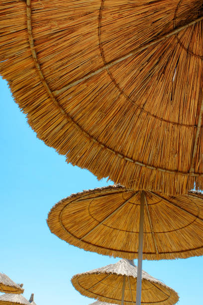 istock Three beach umbrellas made of straw at blue sky background 803619544