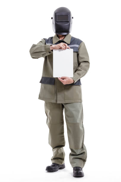 Welder in overalls, and a protective mask on his head demonstrates a blank card stock photo