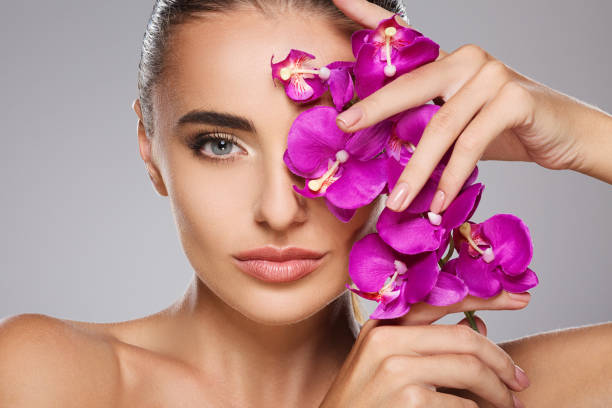 istock Girl with orchid closing one eye 803625722