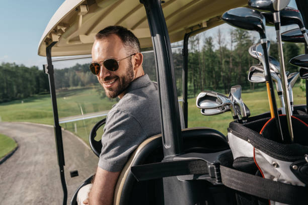 istock smiling man in sunglasses riding golf cart and looking at camera 803639818
