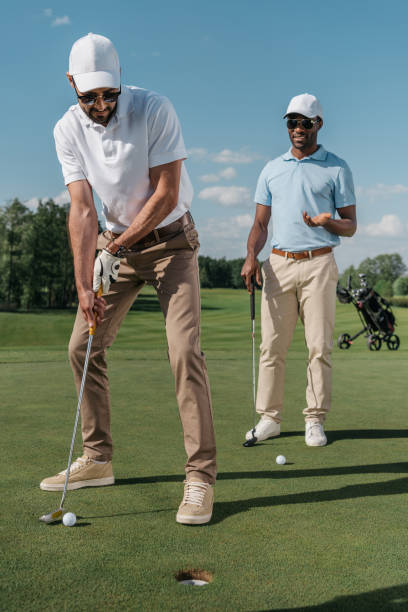 istock young golfer putting ball into hole while his friends standing behind 803640210