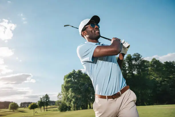 Photo of Smiling african american man in cap and sunglasses playing golf