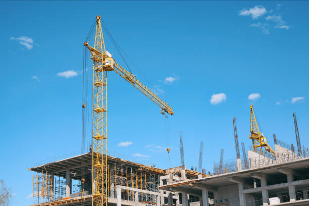 istock Yellow cranes and building under construction against blue sky. 803642968