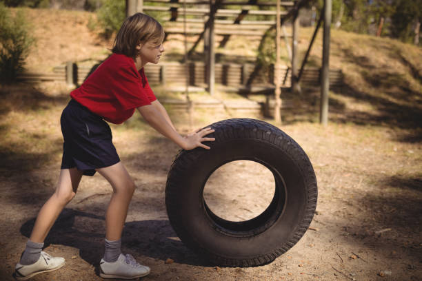 istock Determined girl exercising with huge tyre during obstacle course 803663618