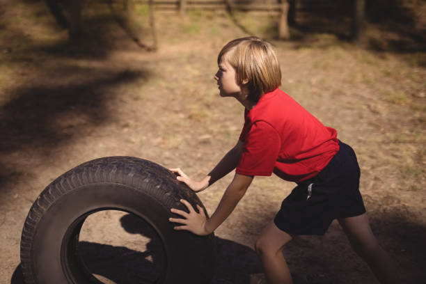 istock Determined girl exercising with huge tyre during obstacle course 803665886