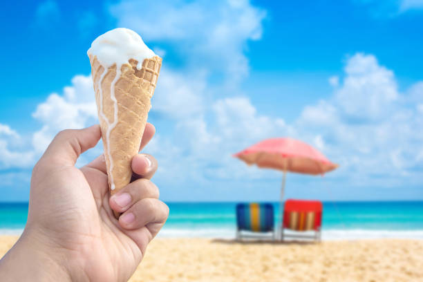 istock Hand holding ice cream cone serve in hot summer day on sky background. 803668868