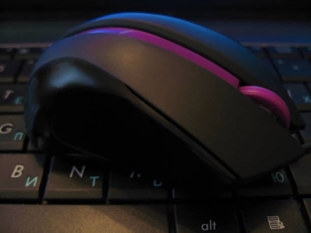 istock Computer mouse with violet strip laying on black keybord of notebook 803687158