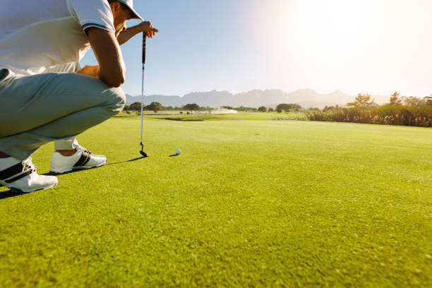 Pro golf player aiming shot with club on course Pro golf player aiming shot with club on course. Male golfer on putting green about to take the shot. golf concentration stock pictures, royalty-free photos & images