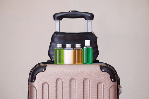 artículos de aseo, pequeñas botellas de plástico de productos de higiene en la maleta de viaje photo
