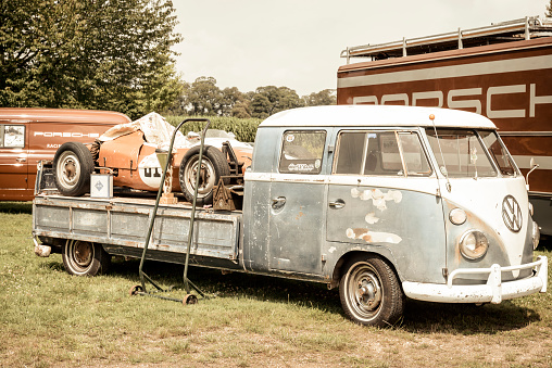 Porsche Formula racing car on a Transporter 1960s Volkswagen Bus flatbed pick up Double Cab. There is a Porsche racing truck parked in the background. The cars are on display during 2016 Classic Days at Dyck castle in Germany.