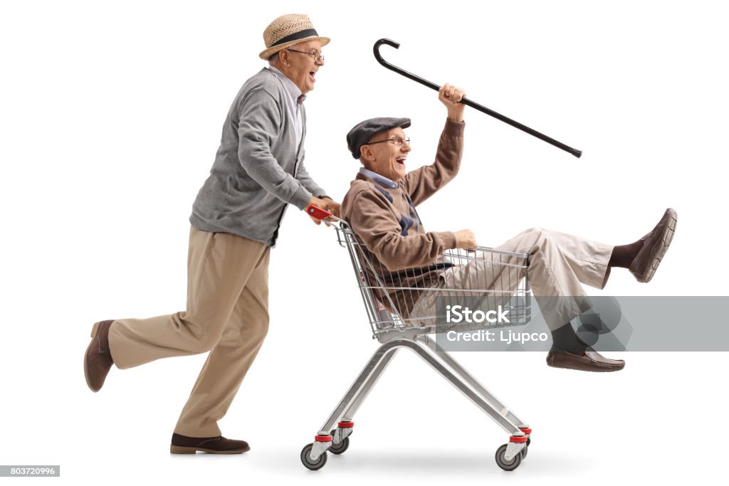 Senior pushing another senior in a shopping cart Senior pushing another senior in a shopping cart isolated on white background Senior Adult Stock Photo