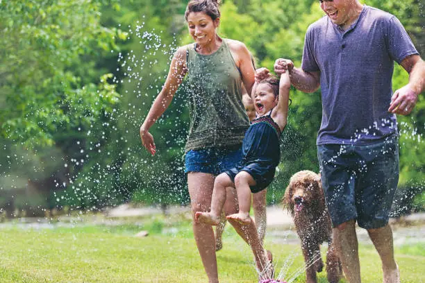 Millennial parents playing with kids in water