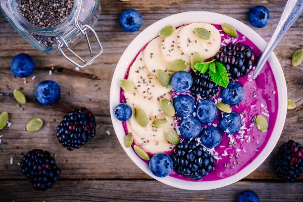 smoothie bowl with fresh blackberries, blueberries, banana, sunflower seeds, pumpkin seeds, chia  seeds and coconut - chia seed spoon food imagens e fotografias de stock