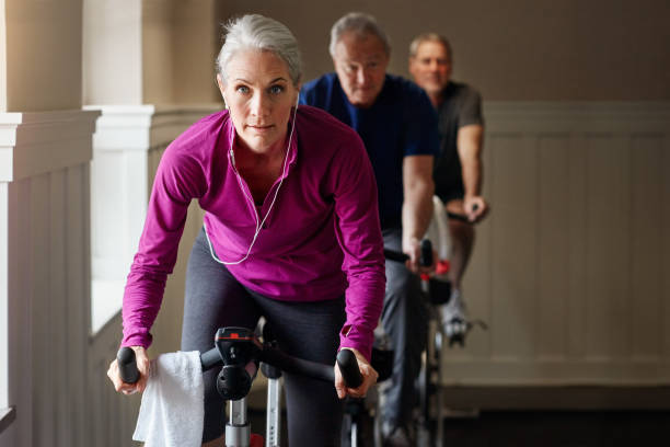 Age won't hold us back Shot of a group of people having a exercising class at the gym exercise bike stock pictures, royalty-free photos & images