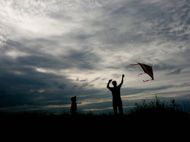istock man and little boy flying a kite at sunset 803758604