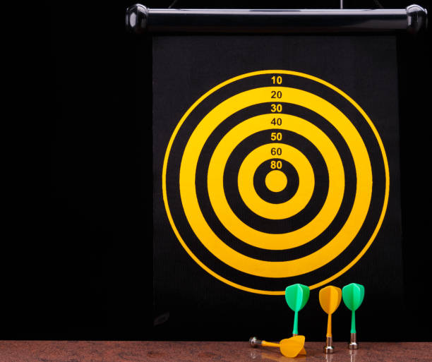 istock Magnetic dart arrows on granite surface and dart board background. 803787258