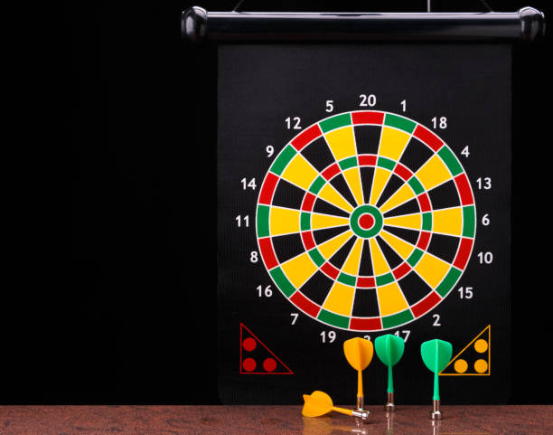 istock Magnetic dart arrows on granite surface and dart board background. 803789450