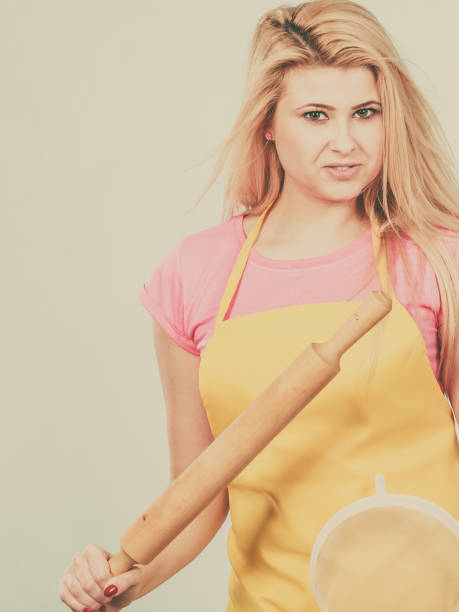 istock Woman wearing apron holding colander and rolling pin 803794998