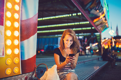 Smiling girl texting at the amusement park