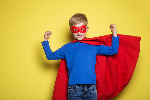 Boy in superhero costume against a yellow background.