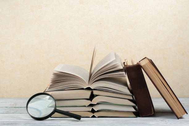 istock Open book, hardback colorful books on wooden table. Magnifier. Back to school. Copy space for text. Education business concept 803829446