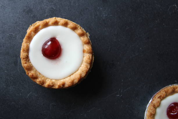 istock Cherry bakewell tarts in foil cases on dark background 803831970