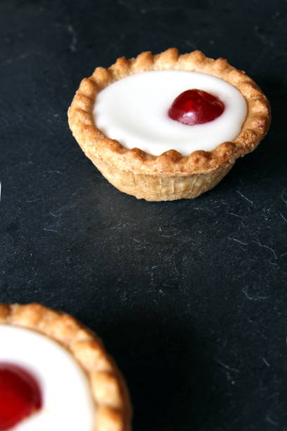 Cherry bakewell tarts on dark background Cherry bakewell tarts on dark background bakewell photos stock pictures, royalty-free photos & images