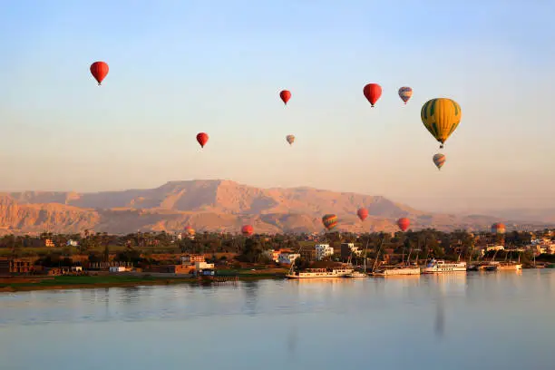 Many Hot air balloons floating over the Nile River in Luxor at sunrise