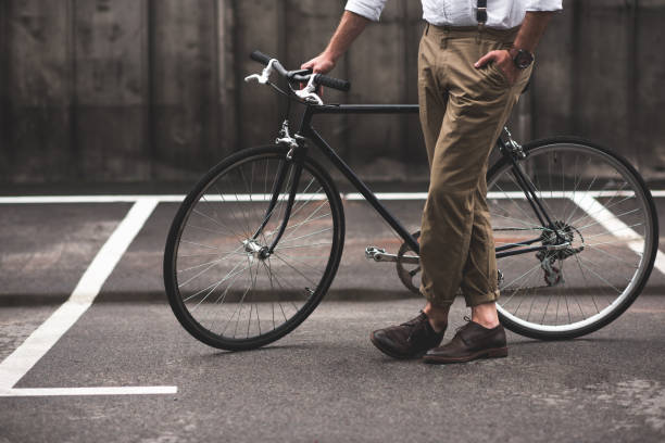 istock low section of stylish man in brown pants standing with bicycle 803837558