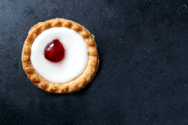 Cherry bakewell tart in foil case on dark background Cherry bakewell tart in foil case on dark background bakewell photos stock pictures, royalty-free photos & images