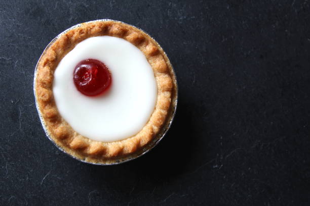 istock Cherry bakewell tart in foil case on dark background 803842832