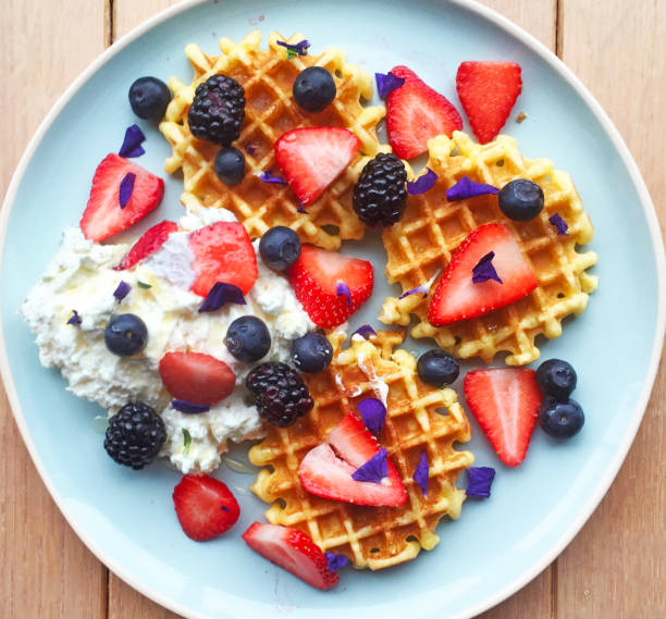 벨기에 와플 크림, 시럽, 식용 꽃, 딸기를 얹은. 홈메이드 아침 식사 소박한 나무 배경에 공중 볼 수 있습니다. - waffle waffled belgian waffle food 뉴스 사진 이미지