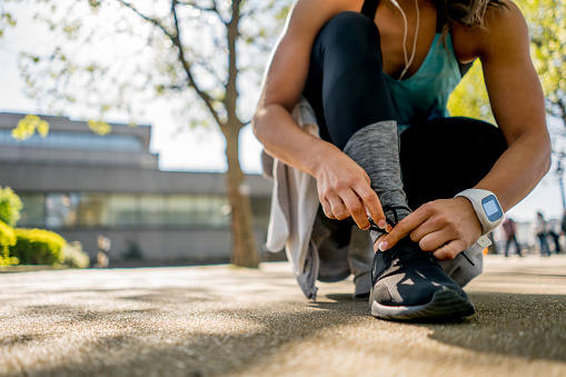 Close-up on a female runner tying her shoelace outdoors - women in sports concepts