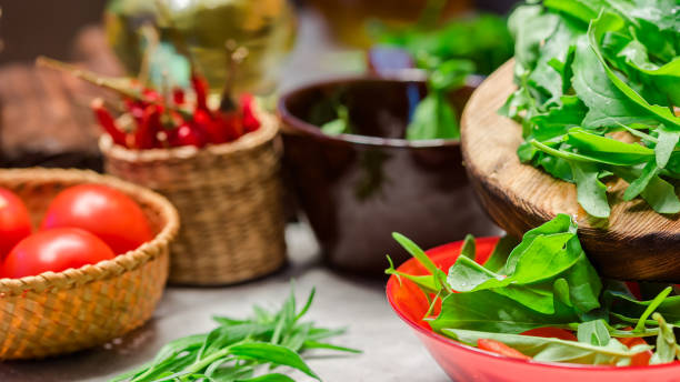 Fresh vegetable salad cooking Adding arugula into the bowl with fresh vegetable salad. Close up tarragon cutting board vegetable herb stock pictures, royalty-free photos & images