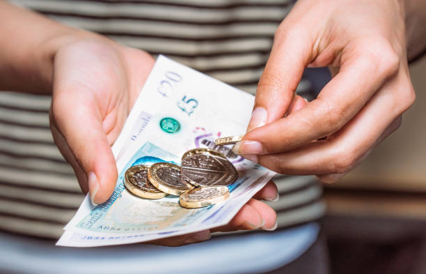 Paying with British currency Detail of a woman counting money for payment. one pound coin stock pictures, royalty-free photos & images