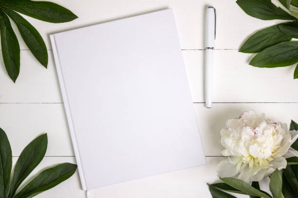 Blank white book, journal, wedding guestbook, notebook mockup. Blank white book, journal, wedding guestbook, notebook mockup. Object for design and branding. White peony and wooden texture, top view. guest book photos stock pictures, royalty-free photos & images