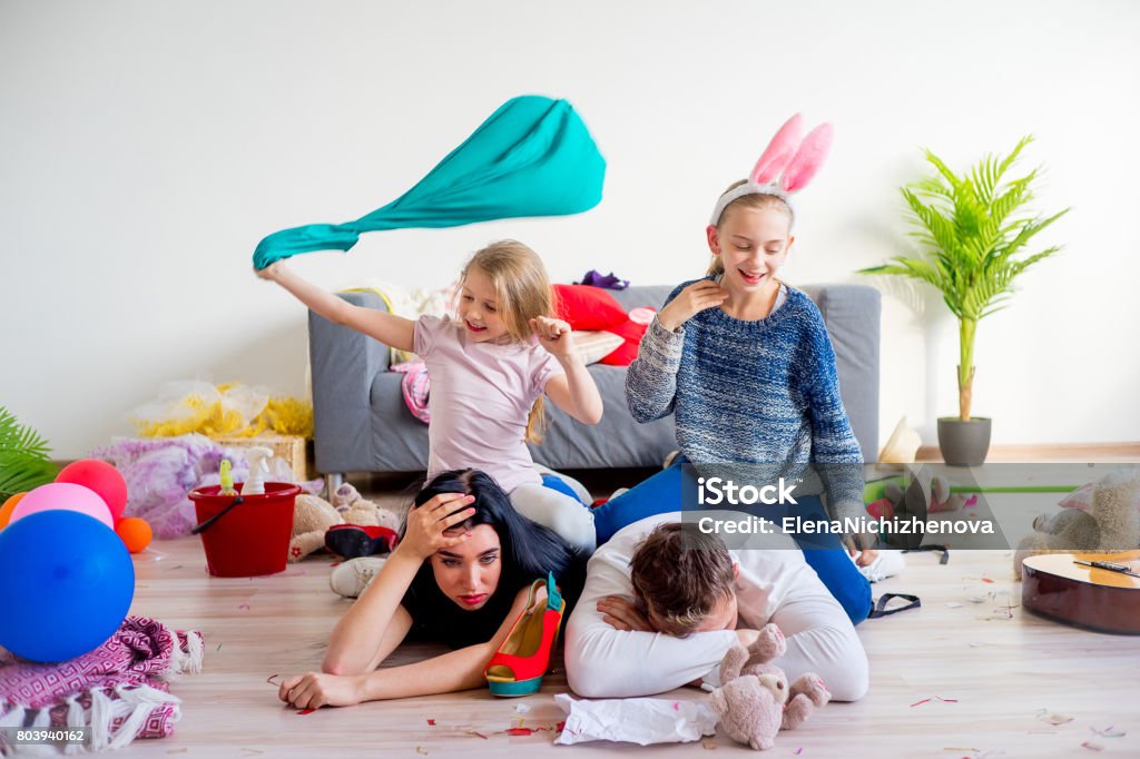 Tired parents and romping kids Tired parents lying on floor and their romping kids Child Stock Photo